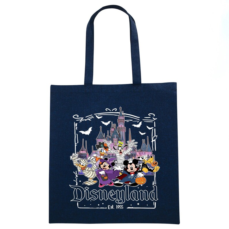 May include: Navy blue tote bag featuring a Disneyland Halloween design. The graphic includes Disney characters in costumes, a castle, bats, and the text "Disneyland Est. 1955". The bag has a rectangular shape and two handles.