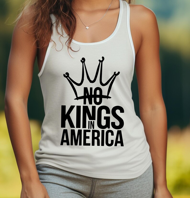 May include: White vest top featuring a black crown design and the words "NO KINGS IN AMERICA". The top has a scoop neckline and white trim. The text is in a bold, sans-serif font.