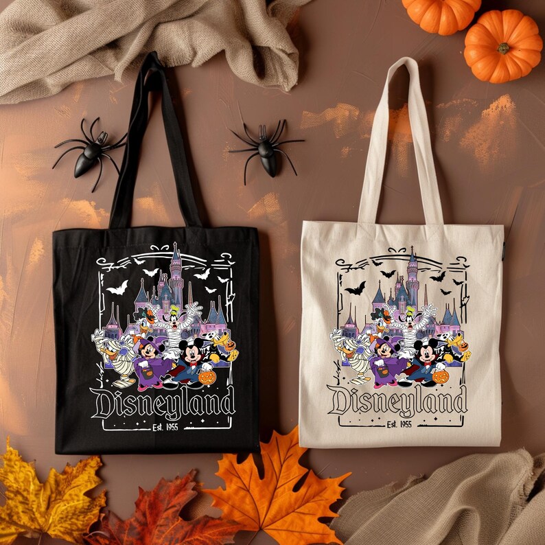May include: Two tote bags, one black and one off-white, featuring a Disneyland Halloween design. The design includes cartoon characters, a castle, bats, and the text "Disneyland Est. 1955". Decorative spiders and pumpkins are also present.