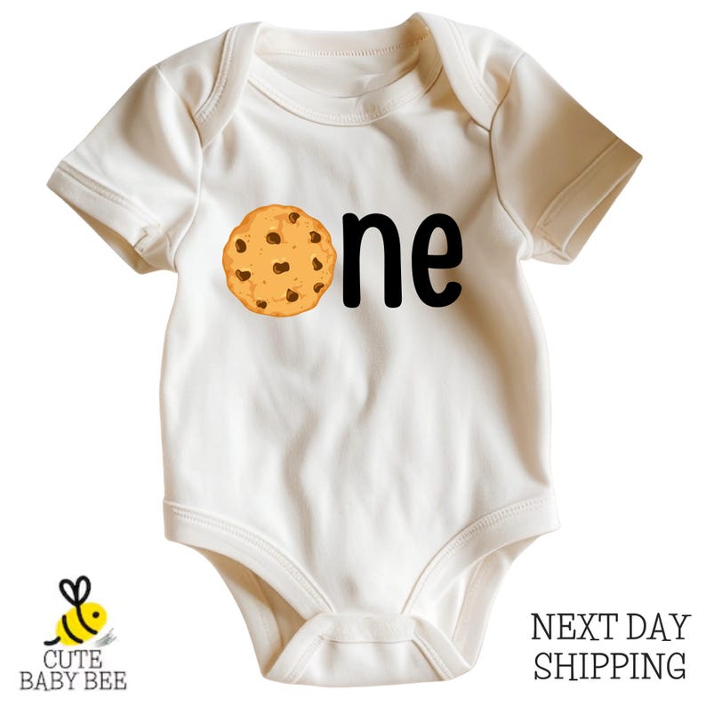 A white baby onesie with a cookie graphic printed on it.