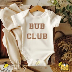 May include: White baby onesie with brown text that reads "BUB CLUB".