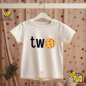 a white t - shirt with a cookie and the word tw on it