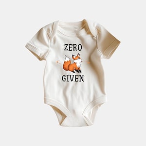 May include: A cream-colored baby onesie with short sleeves features a cartoon fox with the text "ZERO GIVEN" printed on the front.