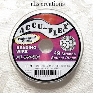 Pode incluir: Um carretel de fio para miçangas Accu-Flex "Classic" com 49 fios. A embalagem apresenta um logotipo de aço inoxidável com revestimento transparente e texto indicando um comprimento de 9,1 m e um diâmetro de 0,61 mm. Fabricado no Japão.
