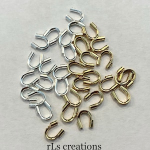 May include: A close-up of a pile of gold and silver jump rings. The jump rings are small and have a U-shape. The jump rings are used for jewelry making.