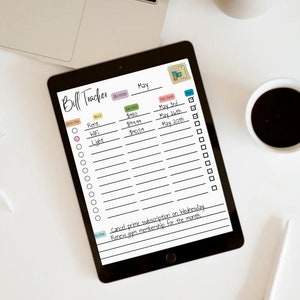 May include: A digital tablet displaying a bill tracker for the month of May. The tracker includes a list of bills, their amounts, and due dates. There are checkboxes next to each bill to mark them as paid. The tablet is on a white surface with a cup of coffee and a stylus pen.