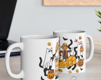 May include: Two white ceramic mugs with a Halloween-themed design. The design features cartoon cats dressed as ghosts, a scarecrow, pumpkins, bats, and autumn leaves. The mugs are on a light-colored surface.