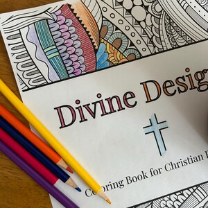 Puede incluir: Un libro para colorear con una portada blanca y el título "Divine Designs" en texto naranja y negro. La portada también presenta una cruz y el texto "Coloring Book for Christian Families". La portada tiene un diseño parcialmente coloreado con rosa, azul, naranja y amarillo.