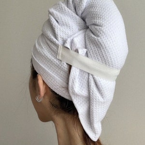 May include: A white towel turban with an elastic band to hold it in place. The towel is wrapped around the head and secured with the elastic band.