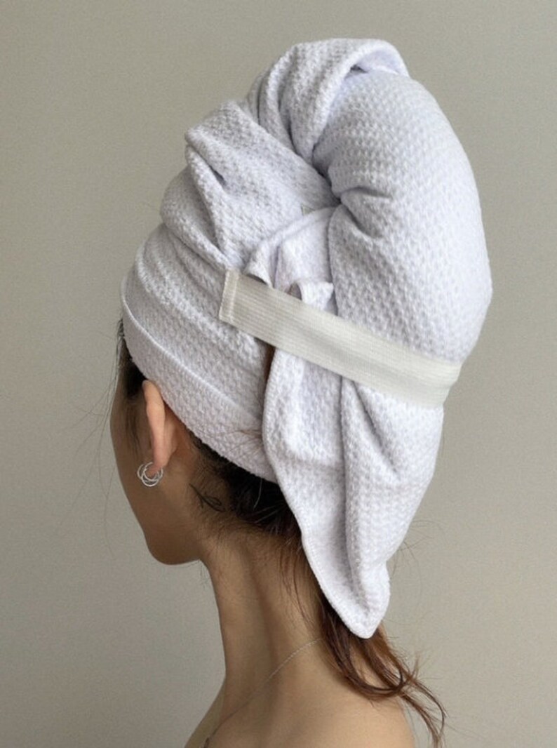 May include: A white towel turban with an elastic band to hold it in place. The towel is wrapped around the head and secured with the elastic band.