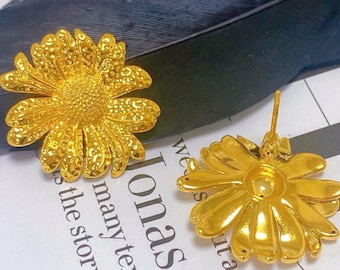Puede incluir: Un par de pendientes de botón de flor de margarita de color dorado con una pequeña perla en el centro de cada flor.