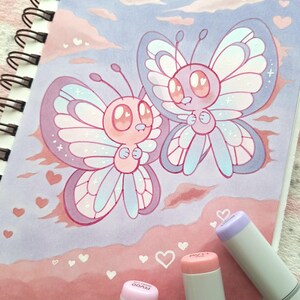 May include: A charming illustration featuring two cartoon butterflies with large eyes and pastel wings. The butterflies are pink, blue, and purple, set against a soft pink and blue background with heart shapes. Markers are visible in the foreground.