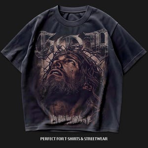 May include: Dark grey t-shirt with a distressed graphic of a man wearing a crown of thorns, the word "GOD" above and the text "WHY HAVE YOU FORSAKEN ME" below. The shirt is designed for streetwear.