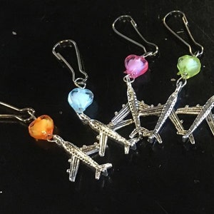 May include: Five silver airplane charms with different colored heart-shaped beads. The beads are orange, blue, pink, and green.
