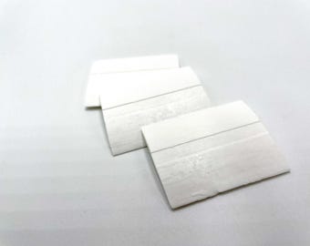 Peut inclure: Trois objets blancs, rectangulaires et texturés avec des lignes horizontales sont disposés sur une surface blanche. Les objets semblent être faits d'un matériau solide, peut-être de la pierre ou de la céramique. L'éclairage est doux et l'effet général est épuré et minimaliste.