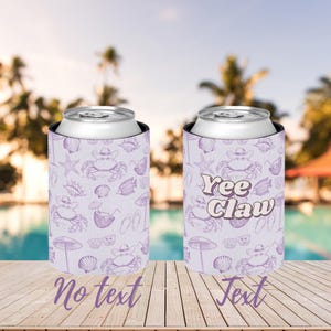 May include: Two can coolers with a light purple background and a repeating pattern of crabs wearing cowboy hats, seashells, and sunglasses. One cooler says "Yee Claw" in a cursive font.