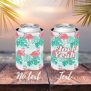 Könnte beinhalten: Zwei rosafarbene Flamingo-Getränkedosenkühler mit tropischem Blatt-Muster. Ein Kühler hat den Text "Flock Yeah" darauf.