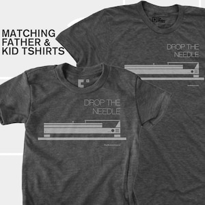 May include: Two dark gray t-shirts with the text "DROP THE NEEDLE" and a graphic of a record player. The shirts are labeled "Matching Father & Kid Tshirts".