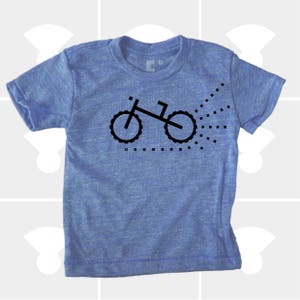 Puede incluir: Una camiseta azul de manga corta con un gr&aacute;fico negro de una bicicleta con un rastro de puntos detr&aacute;s.