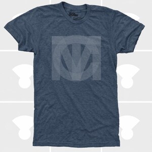 Pu&ograve; includere: Una maglietta blu girocollo con un design a logo circolare grigio chiaro sbiadito sul davanti. Il logo sembra essere le iniziali "M" e "V" intrecciate. La maglietta &egrave; realizzata in un tessuto morbido e strutturato.