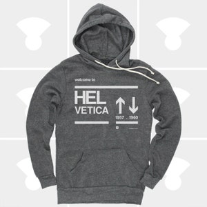 K&ouml;nnte beinhalten: Ein dunkelgrauer Kapuzenpullover mit dem Aufdruck "welcome to HELVETICA 1957 - 1960" auf der Vorderseite.