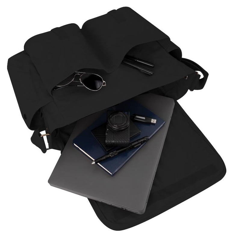 May include: Black backpack with several compartments, open to show contents. Inside are a laptop, camera, notebook, pens, USB drive, and sunglasses. The bag is made of a durable material and has a sleek, modern design.