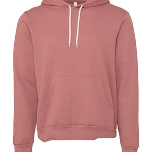 May include: A solid-colored, dusty rose hoodie with a kangaroo pocket and a drawstring hood. The hoodie has long sleeves and a ribbed hem and cuffs. The white drawstrings are visible against the pink fabric. The hoodie is made of a soft, comfortable material.