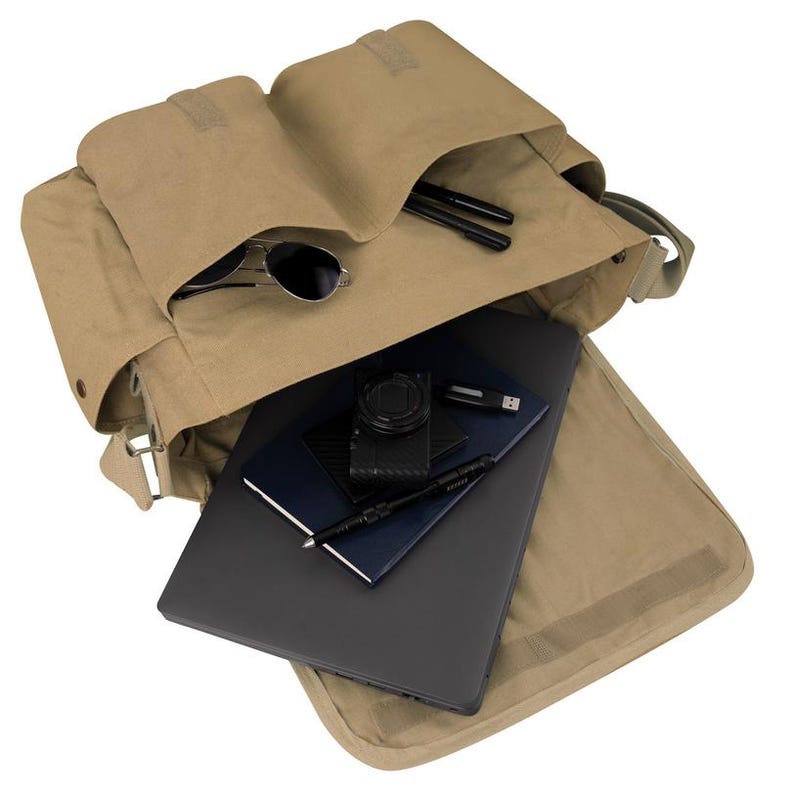 May include: A tan canvas messenger bag, open to reveal contents. Inside are a laptop, notebooks, a camera, a USB drive, pens, and sunglasses. The bag has multiple compartments and a flap closure.