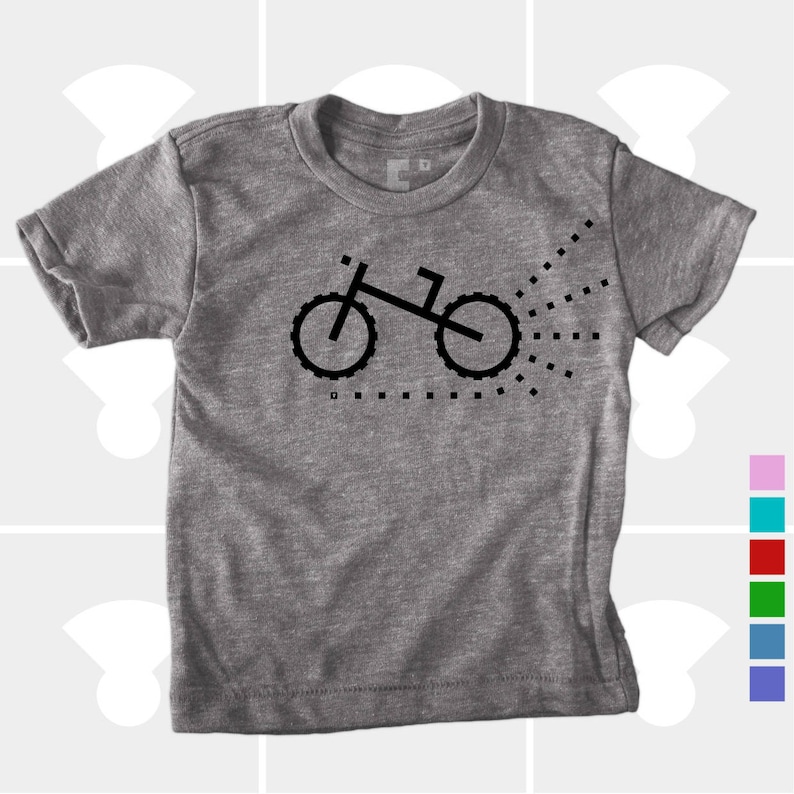 Puede incluir: Una camiseta gris jaspeada con un gr&aacute;fico de bicicleta pixelada en negro. La bicicleta est&aacute; orientada hacia la derecha y tiene un rastro de puntos detr&aacute;s.