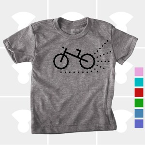 Puede incluir: Una camiseta gris jaspeada con un gr&aacute;fico de bicicleta negra y un rastro de puntos detr&aacute;s.
