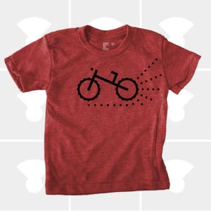 Puede incluir: Camiseta roja con un gr&aacute;fico negro de una bicicleta con un rastro de puntos detr&aacute;s.