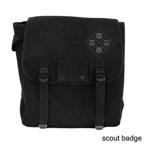May include: Black canvas messenger bag with a flap closure and adjustable straps. The bag features a small emblem of four cat faces and the text "scout badge" at the bottom.