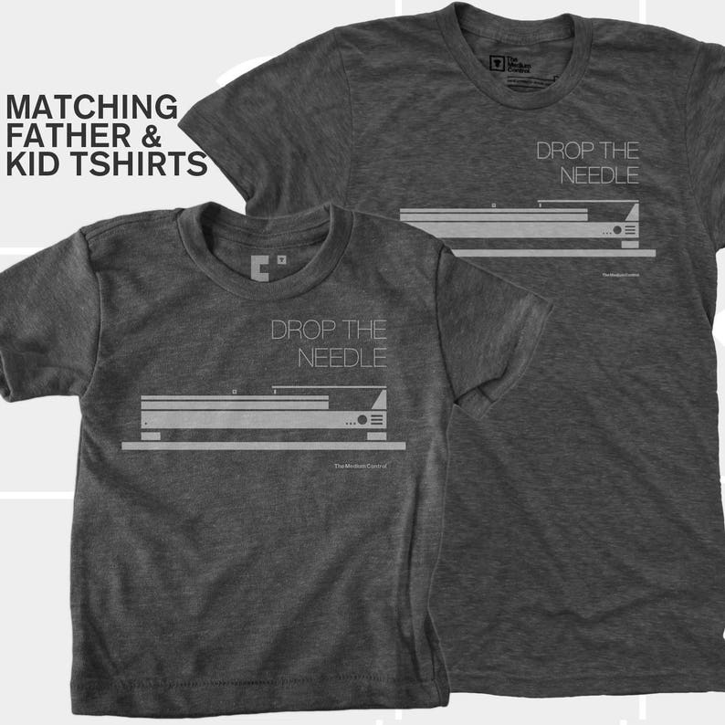 May include: Two dark gray t-shirts with the text "DROP THE NEEDLE" and a graphic of a record player. The shirts are labeled "Matching Father & Kid Tshirts".