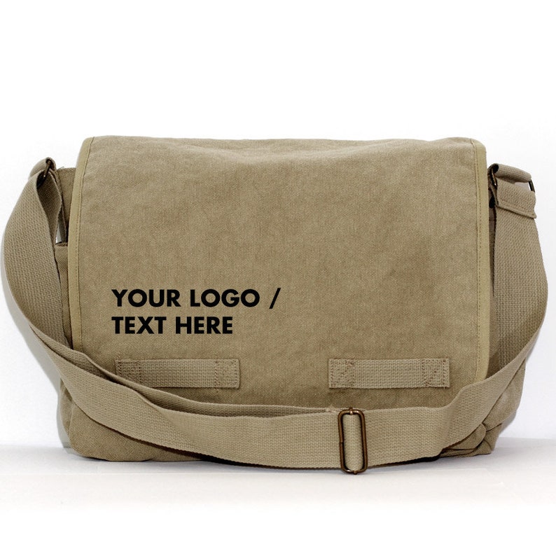 May include: A tan messenger bag with a flap closure and adjustable shoulder strap. The bag features the text "YOUR LOGO / TEXT HERE" in black. The bag has a rectangular shape and a metal buckle.