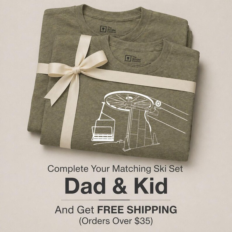 May include: Two olive green crew neck t-shirts stacked and tied with a cream-colored ribbon. The top shirt features a white line art graphic of a ski lift chair and tower. The interior neck label reads The Sonder Control.