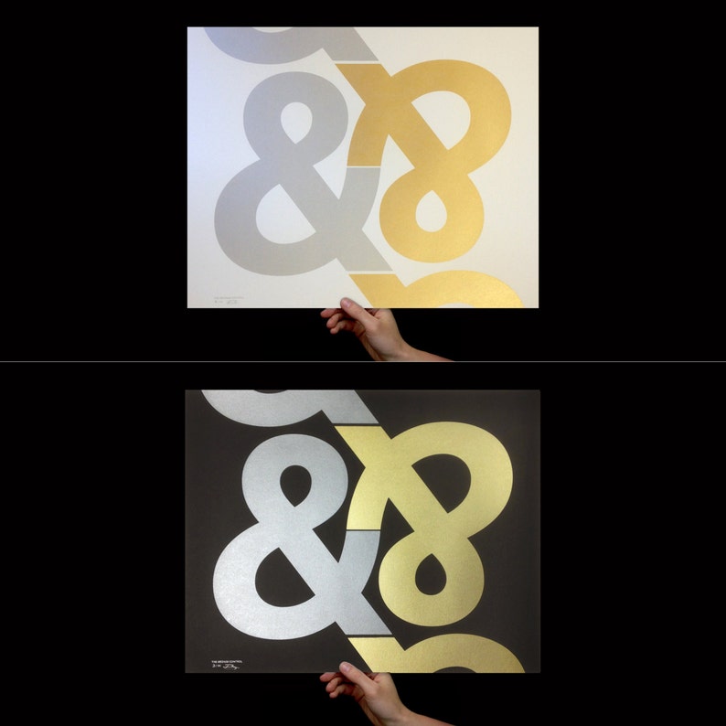 May include: Two square art prints, one on white and one on black, each featuring a large, overlapping ampersand and number eight design. One print has silver and gold elements, the other has silver and gold elements.