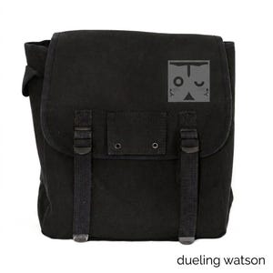 May include: Black canvas messenger bag with a flap closure, two adjustable straps, and a small pocket. The bag features a gray graphic of a cat's face and the text "dueling watson" at the bottom.