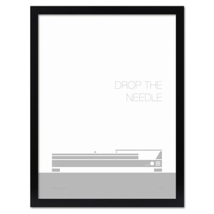 May include: A framed print with a minimalist design. The artwork features a gray illustration of a record player with the text "DROP THE NEEDLE" in a light gray font. The print is set against a white background and framed in black.