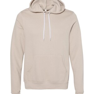 May include: A beige hoodie with a drawstring hood and a kangaroo pocket. The long-sleeved sweatshirt has a relaxed fit and is made of a soft material. The hoodie is a neutral color, suitable for casual wear.