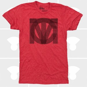 Pu&ograve; includere: T-shirt rosso girocollo con un motivo grafico grigio scuro al centro. Il motivo &egrave; un monogramma stilizzato delle lettere T, M e C all'interno di un quadrato. La maglietta ha maniche corte e una vestibilit&agrave; classica.