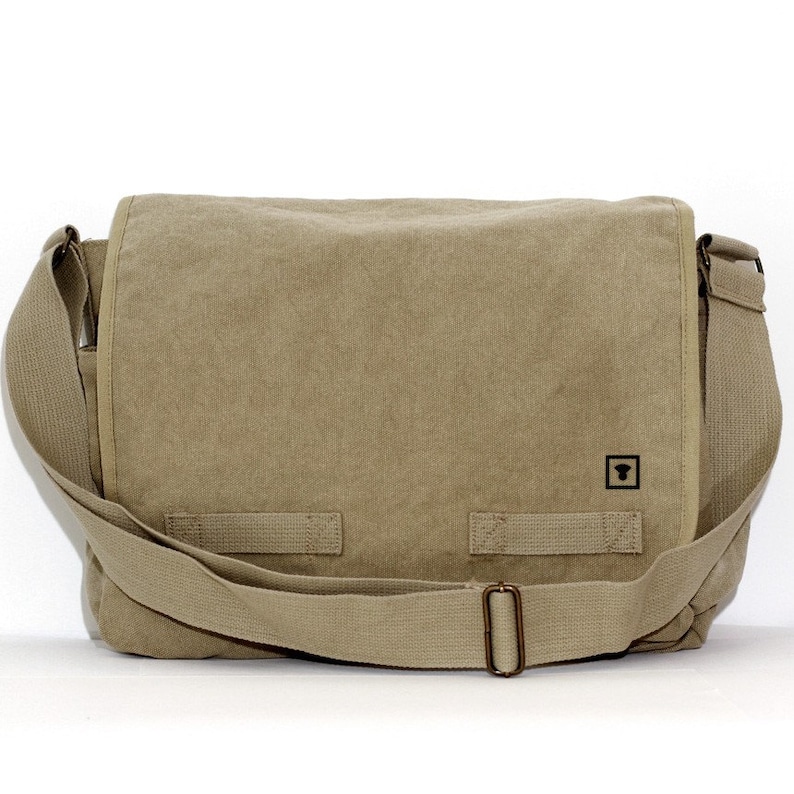 Front view of a blank khaki canvas messenger bag with a minimalist black square logo and antique brass hardware against a white background.