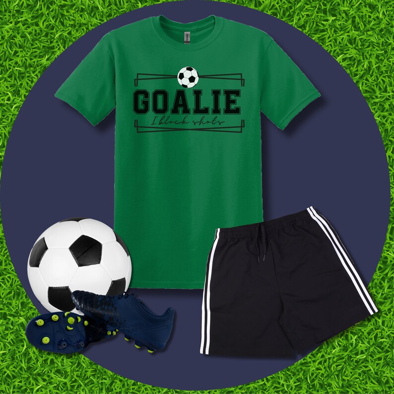 Puede incluir: Camiseta verde con un gr&aacute;fico de bal&oacute;n de f&uacute;tbol blanco y negro y el texto "GOALIE I block shots". Tambi&eacute;n se muestra un bal&oacute;n de f&uacute;tbol negro, tacos de f&uacute;tbol azules y pantalones cortos deportivos negros con rayas blancas.