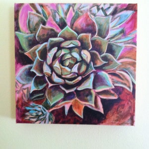 May include: A close-up of a painting of a succulent plant with green, purple, and orange petals. The background is a dark pink and red.
