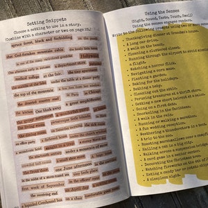 May include: An open book with two pages of writing exercises. The left page, titled Setting Snippets, contains numerous small rectangular paper strips with printed phrases. The right page, titled Using the Senses, features a yellow box with a list of prompts.