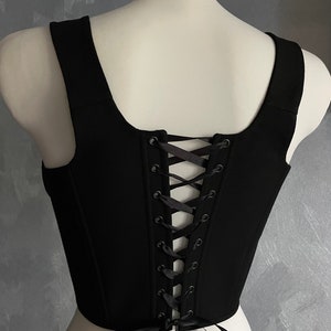 May include: Black sleeveless top with a lace-up back. The top is made of a soft, stretchy fabric and has a fitted silhouette.