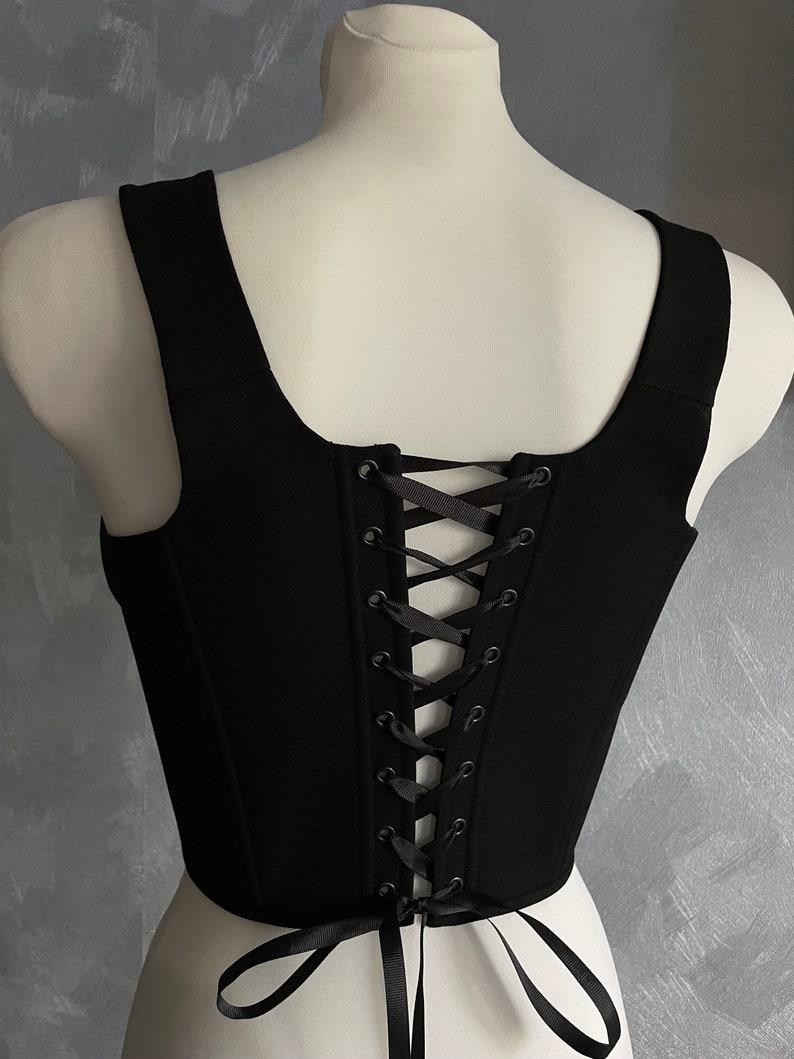 May include: Black sleeveless top with a lace-up back. The top is made of a soft, stretchy fabric and has a fitted silhouette.