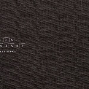 Puede incluir: Primer plano de una tela gris oscura con el texto "MISS MATATABI JAPANESE FABRIC" impreso en ella.