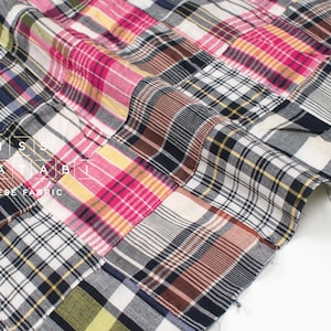 May include: A patchwork fabric featuring a range of plaid patterns in pink, yellow, brown, and blue. The fabric is made from cotton and is ideal for quilting, sewing, and crafting.