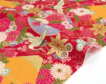 May include: Red Japanese fabric with a floral and crane pattern. The fabric features pink and white flowers, gold leaves, and cranes. The text "JAPANESE FABRIC" is visible. The fabric is folded, revealing a white underside.