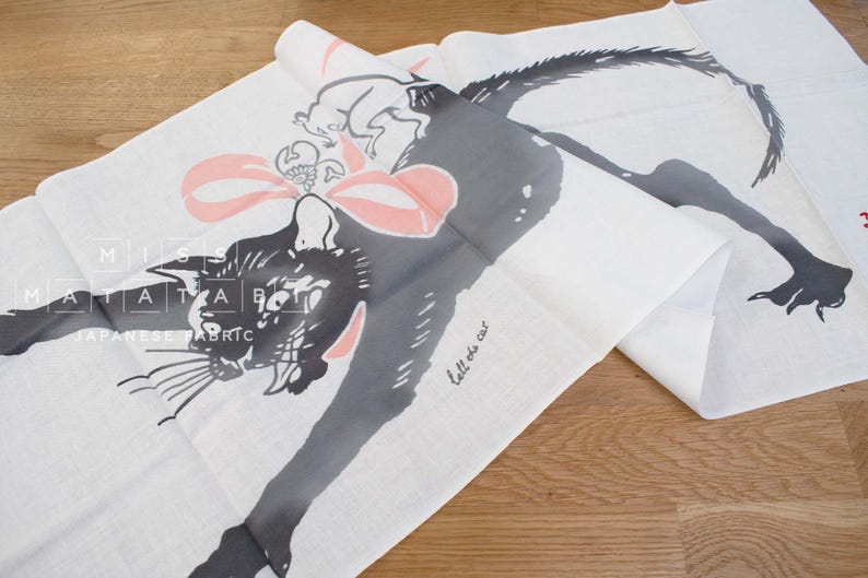 May include: A white fabric panel with a black and white illustration of a cat with a pink bow. The text "tell the cat" is written on the fabric.